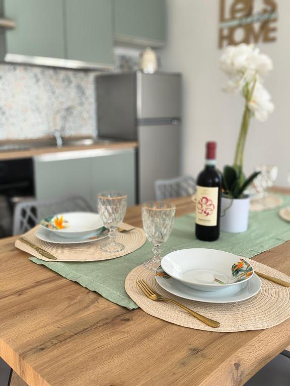 a wooden table with plates and glasses and a bottle of wine at L'Eden in Casarza Ligure