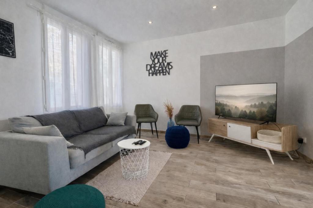 a living room with a couch and a flat screen tv at La Coloc Boho - Saint-Quentin, chambres centre, idéal pro in Saint-Quentin