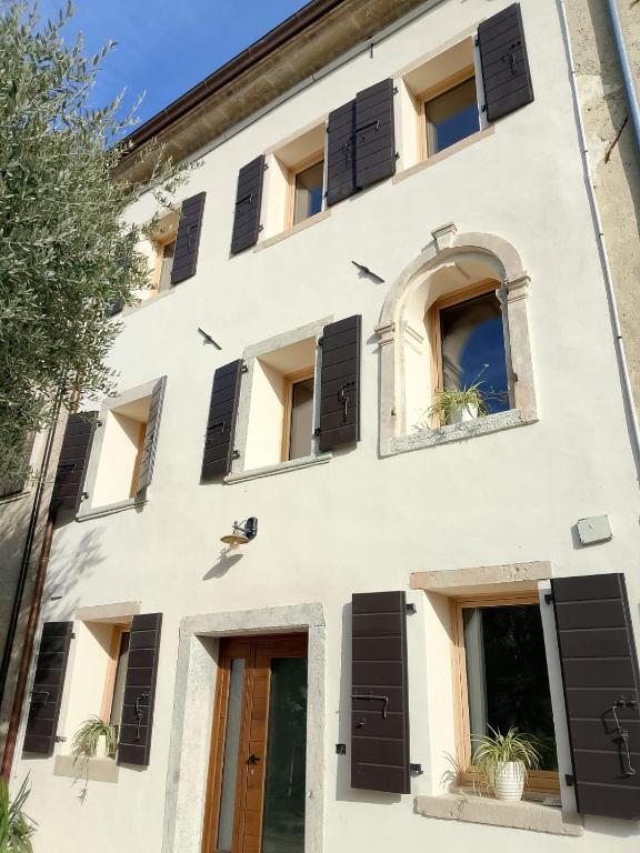 a white building with black shuttered windows at Casa Tormena in Valdobbiadene