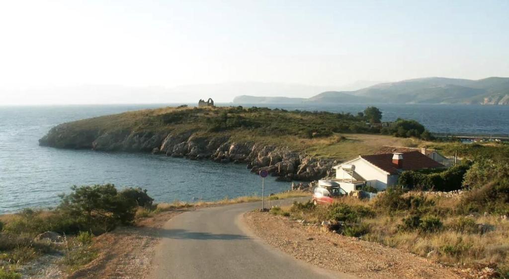 a dirt road next to a large body of water at Maison bord de mer in Risika