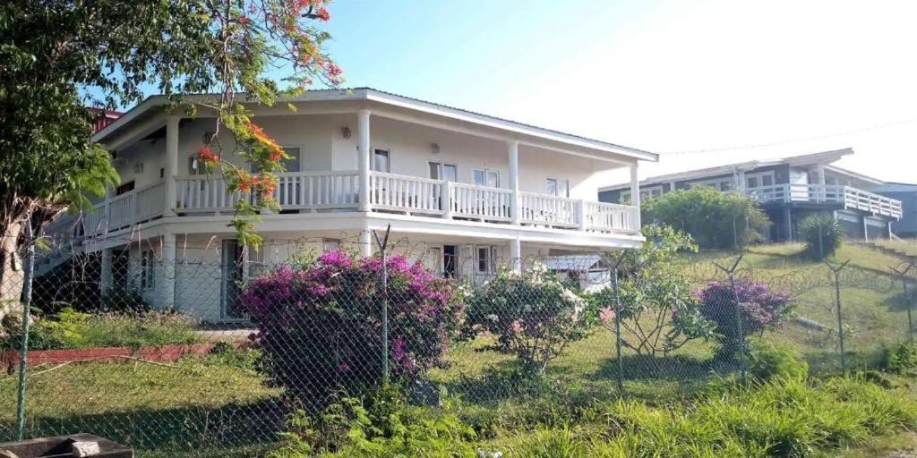 a large white house with a balcony and flowers at A Serene Get Away in Vieux Fort