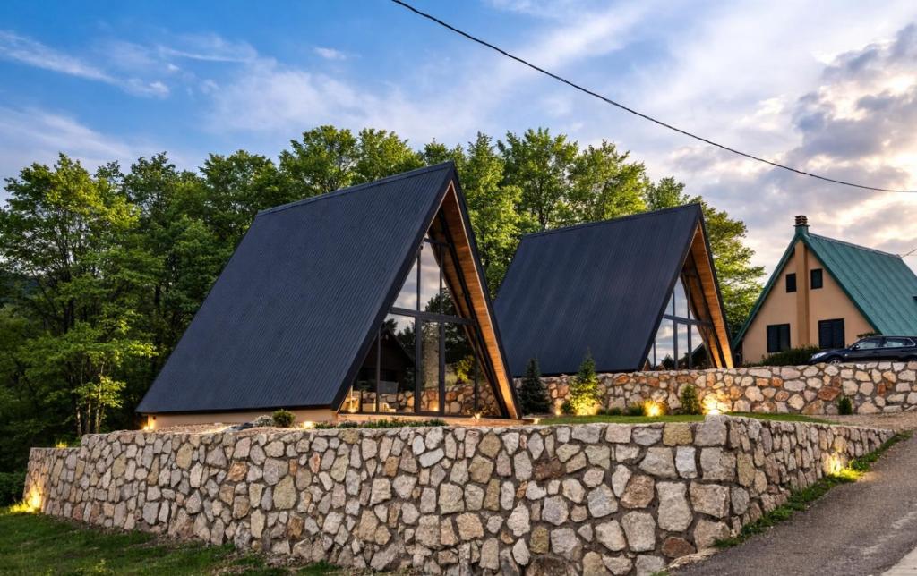 a house with a stone fence and a stone wall at Spa villas Higo in Žabljak