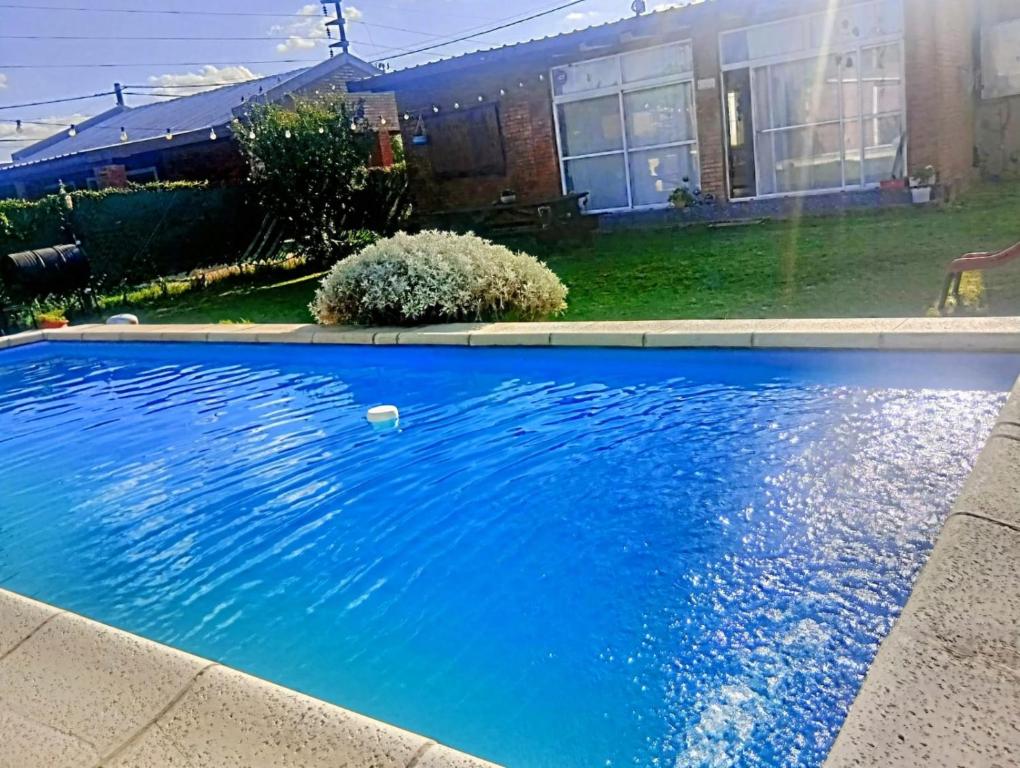 a blue swimming pool in front of a house at Nuestro refugio in Roldán