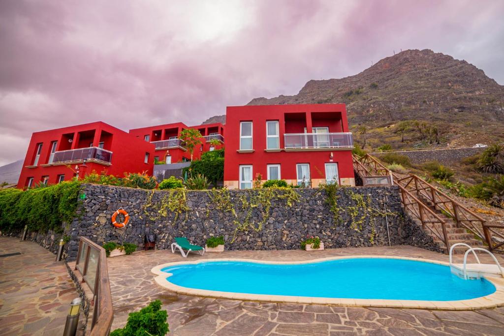a resort with a swimming pool and a building at Viviendas Vacacionales Jardín La Punta in Hermigua
