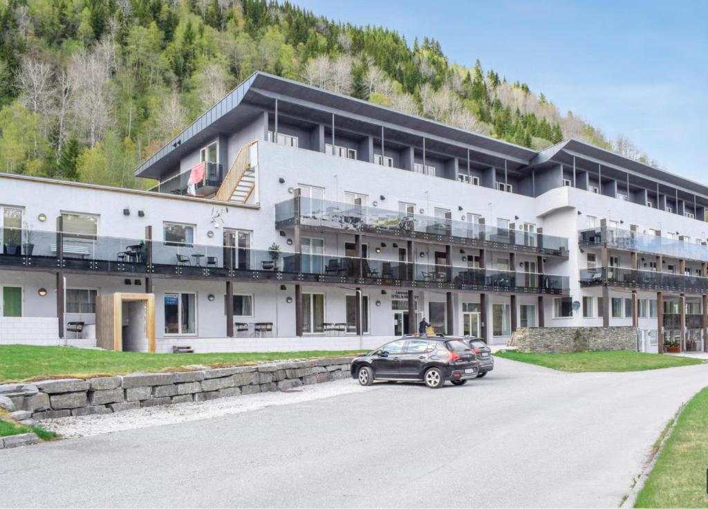 a large white building with cars parked in front of it at Resort by the Lake - Pool & Sauna in Vossevangen