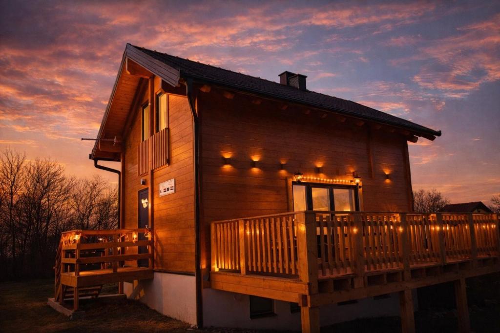 a wooden cabin with a deck with lights on it at Kuća za odmor Kiara in Kolarec