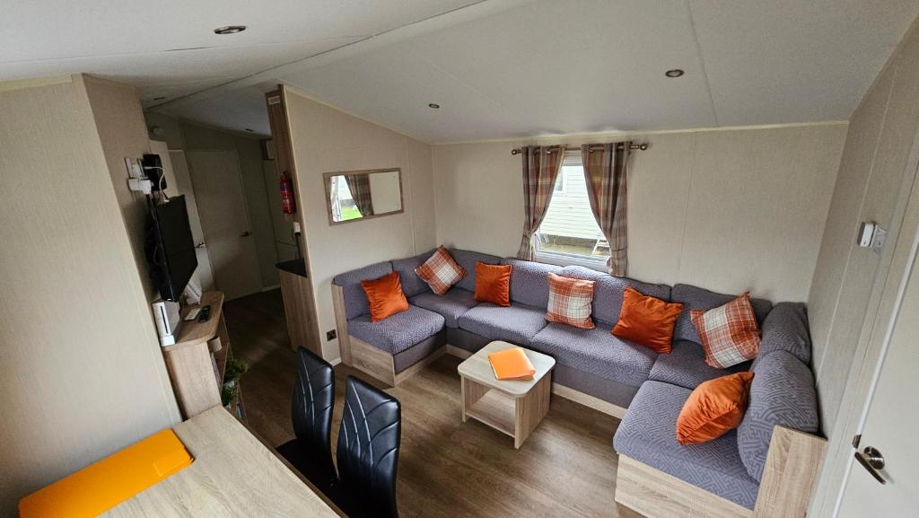 a living room with a blue couch and orange pillows at Great Yarmouth 10 Berth KP Holiday Home - NOW with Linen in Corton