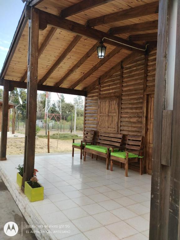a wooden pavilion with benches on a patio at Cabaña El Refugio in La Carrera