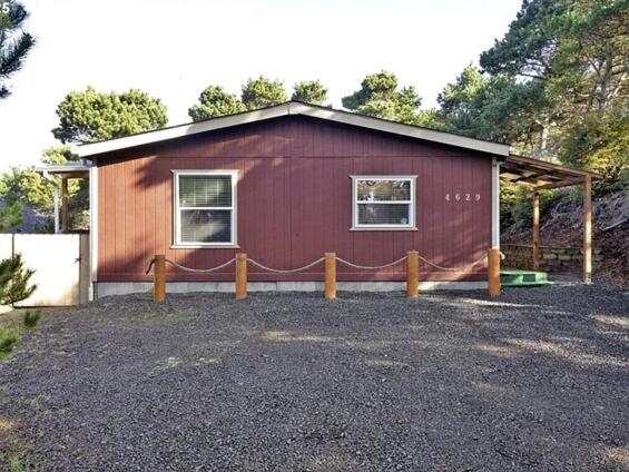 a red house with a fence in front of it at Beach Bum Cabin in Florence