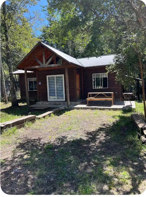 a log cabin with a porch and a bench at Casa familiar en parcela privada Pucón in Pucón