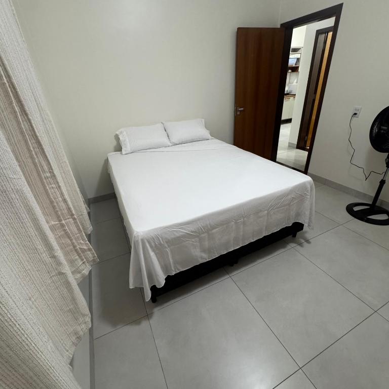 a white bed in a room with a window at Apto Cozi in Sorriso