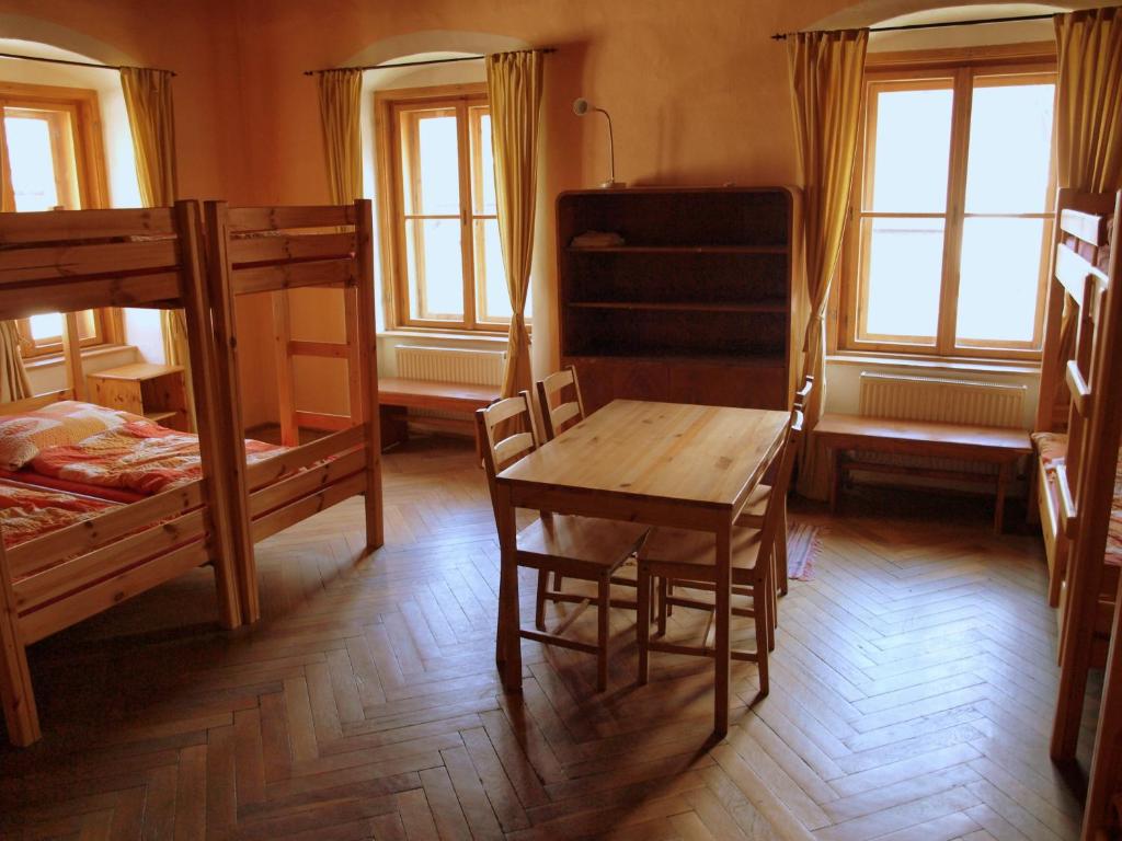 a room with two bunk beds and a table and chairs at Hostel Skautský dom in Banská Štiavnica