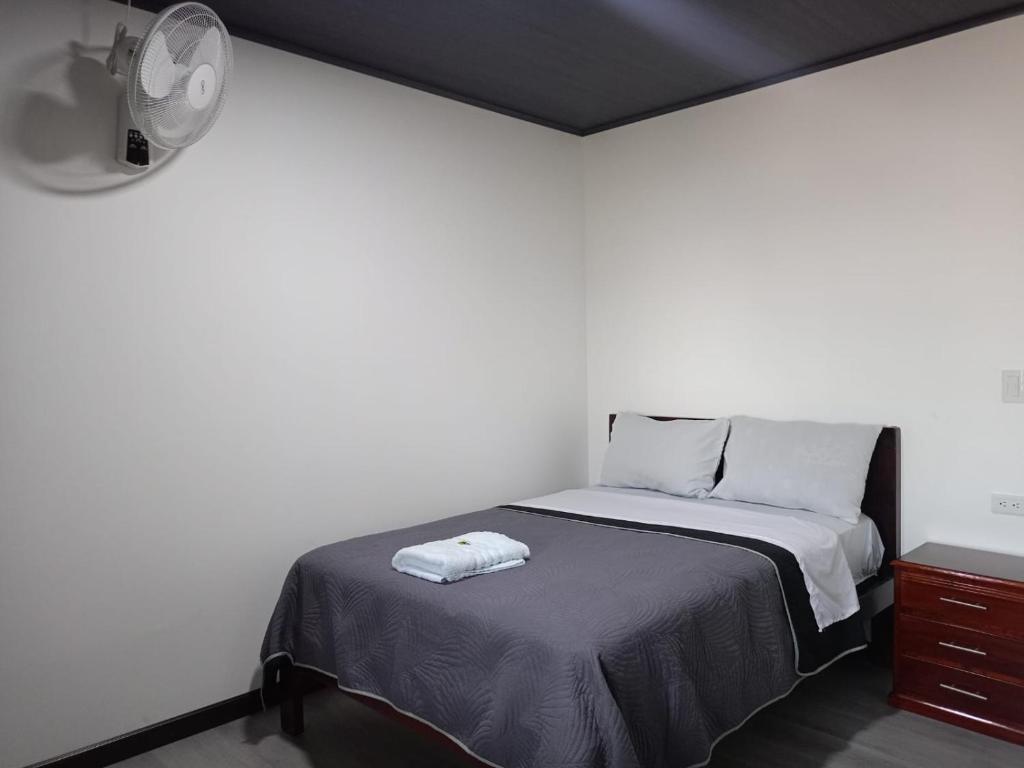 a white bedroom with a bed and a dresser at Hotel Ostatus in El Pangui