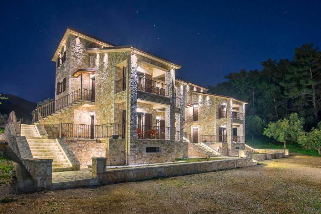 una gran casa de piedra por la noche con luces en Margarita Rooms Sagiada, en Sagiada