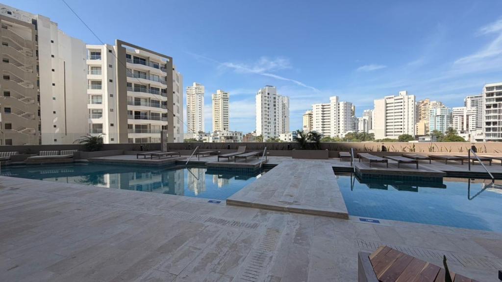 a large swimming pool in a city with tall buildings at Apartamento tipo Loft in Gaira