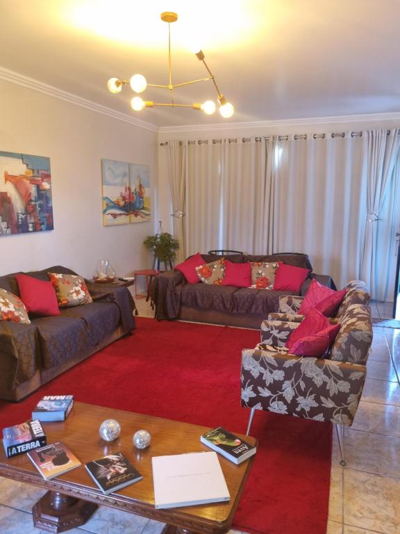 a living room with two couches and a red rug at Quarto suite 1 dorm Prox da Casa de Saude mais salas e estacionamento in Santa Maria