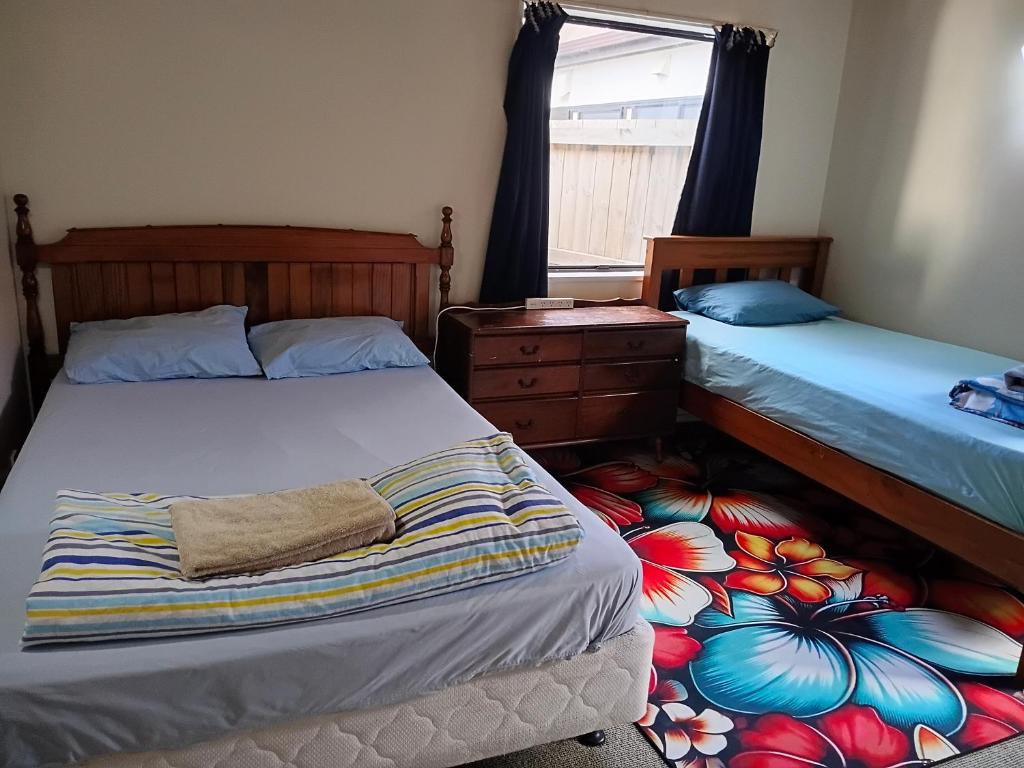 a bedroom with two beds and a dresser at City holiday accommodation in Tauranga