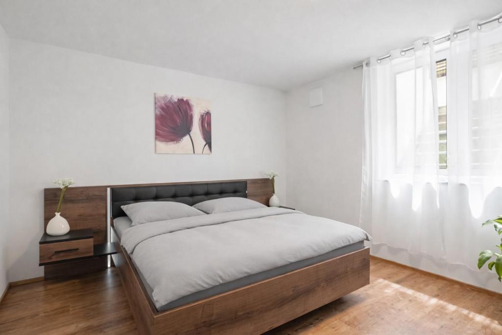 a white bedroom with a bed and a window at Kleine Auszeit in Friedrichshafen