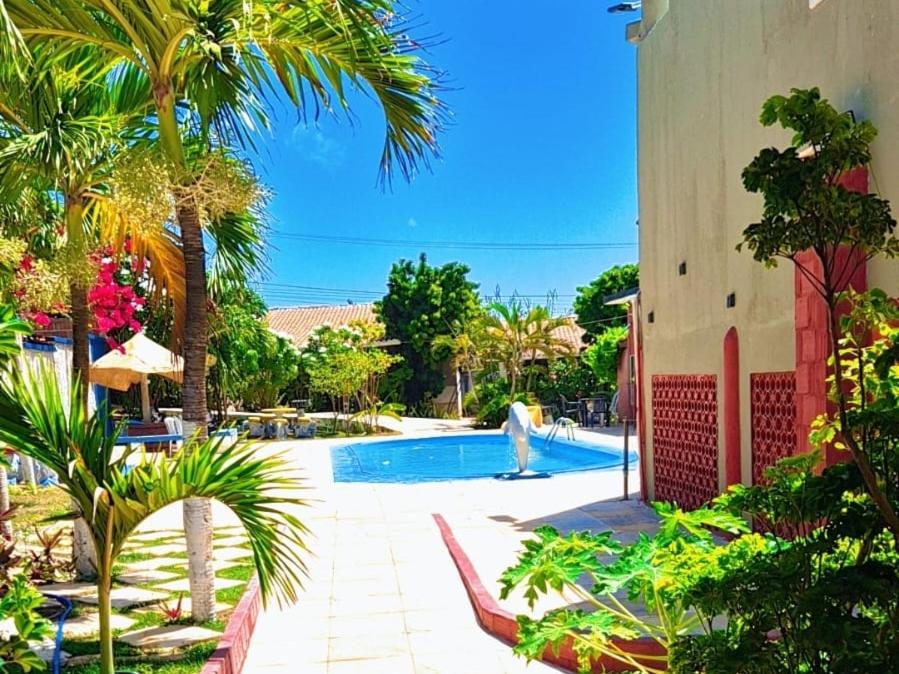 a swimming pool with palm trees next to a building at Casa do Galego no Residência Família in Canoa Quebrada