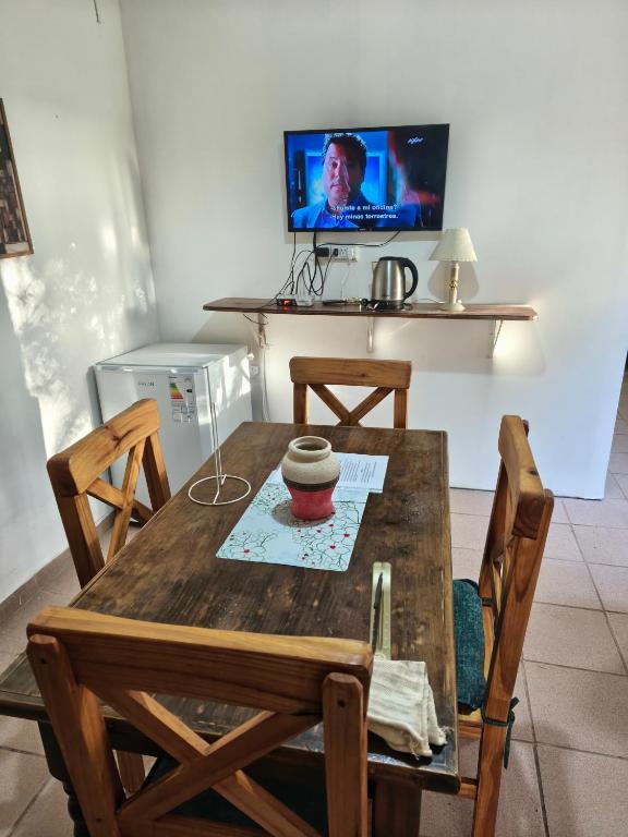 a wooden table with chairs and a television in a room at Cabañas Tierra del molino in General Alvear