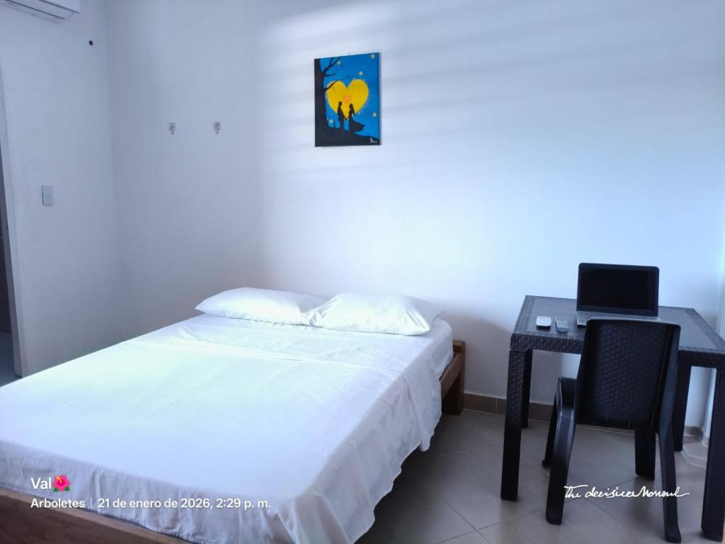 a bedroom with a bed and a desk with a laptop at GTH Hostal in Arboletes