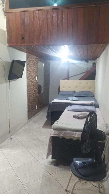 a room with two beds and a chair in it at Kitinete holl in Campos dos Goytacazes