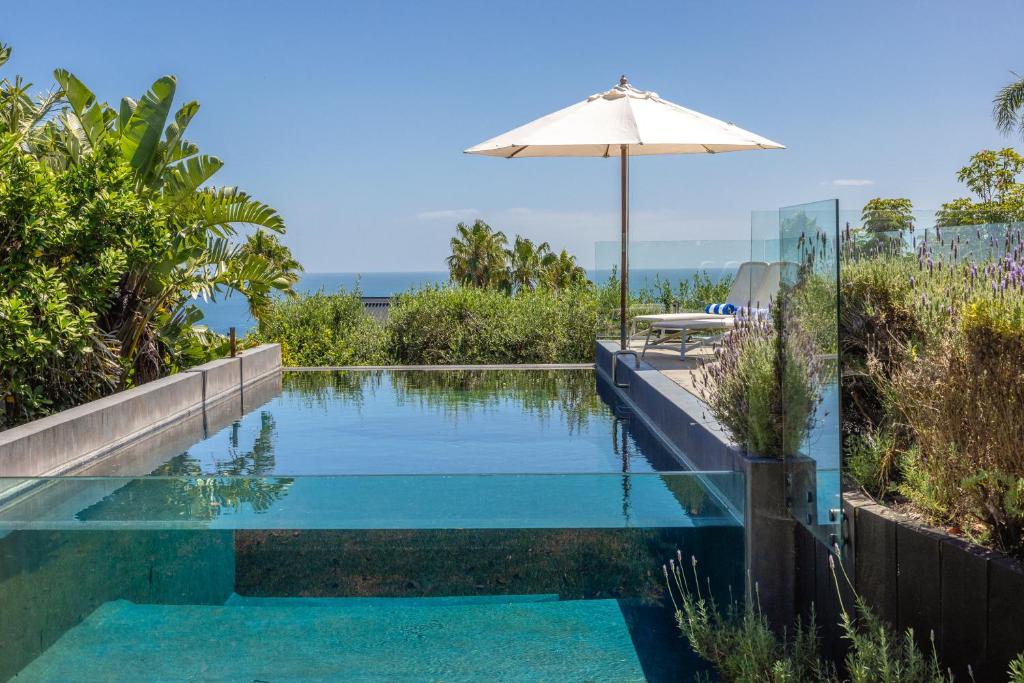 an infinity pool with an umbrella and a table at L'Appartement Bleu in Waiheke Island
