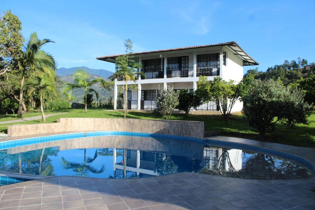 a villa with a swimming pool in front of a house at Hotel Campestre Kambra in Garagoa