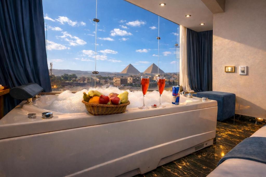 a room with a table with a bowl of fruit and two cocktails at Pharaonic Pyramids Inn & jacuzzi in Cairo