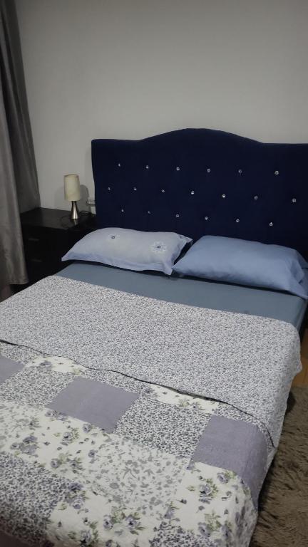 a bed with a blue headboard and pillows on it at Habitaciones Ciudad de la Luna Chia in Chía