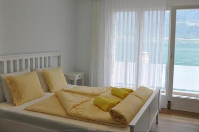 a white bed with yellow pillows in a bedroom at Gersau Hotel Fähri in Gersau