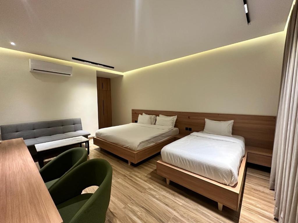 a hotel room with two beds and a couch at Hamsun Shahrah-e-Faisal Extension in Karachi