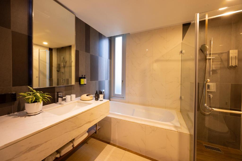 A marble-look bathroom combines a long vanity, bathtub and enclosed glass shower.