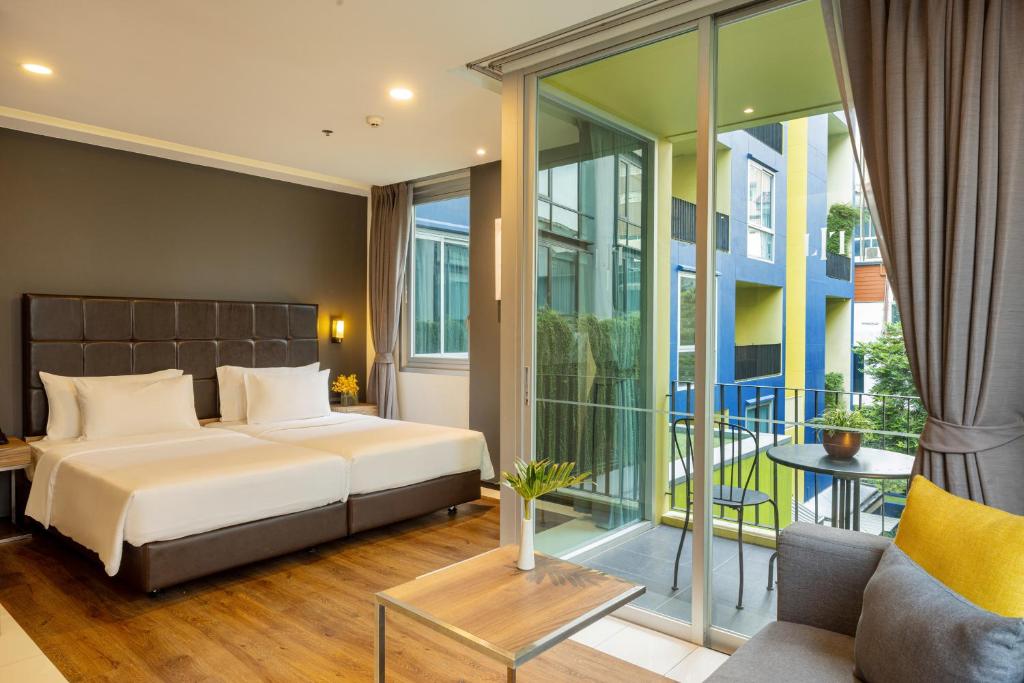 A bedroom with two beds opens directly onto a furnished balcony overlooking the pool area.
