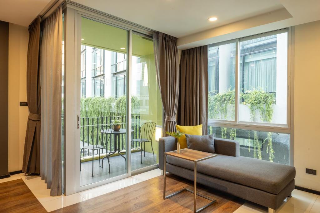 A sitting area with a chaise-style sofa opens onto a furnished balcony through sliding glass doors.