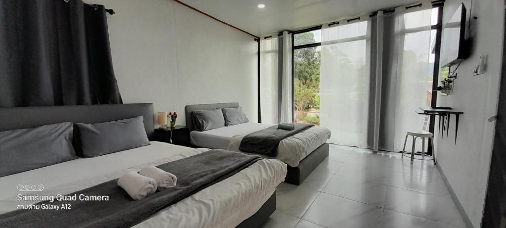 a bedroom with two beds and a large window at lnthanon Laoju เล่าจู in Ban Na Yang