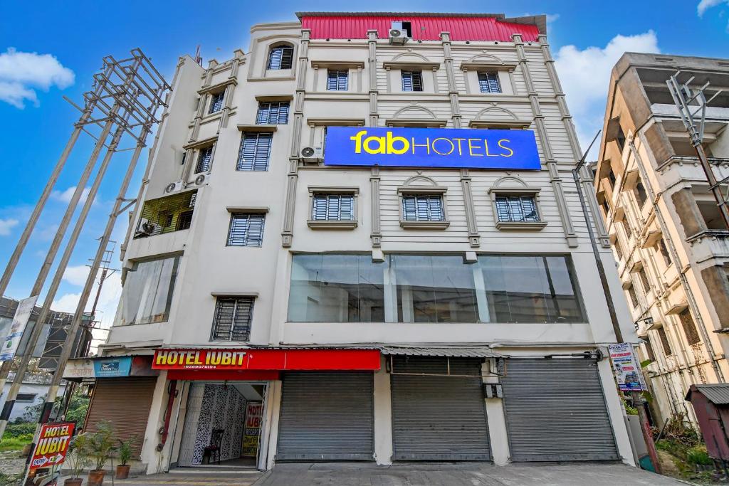 a tall white building with a blue sign on it at FabHotel Iubit in kolkata