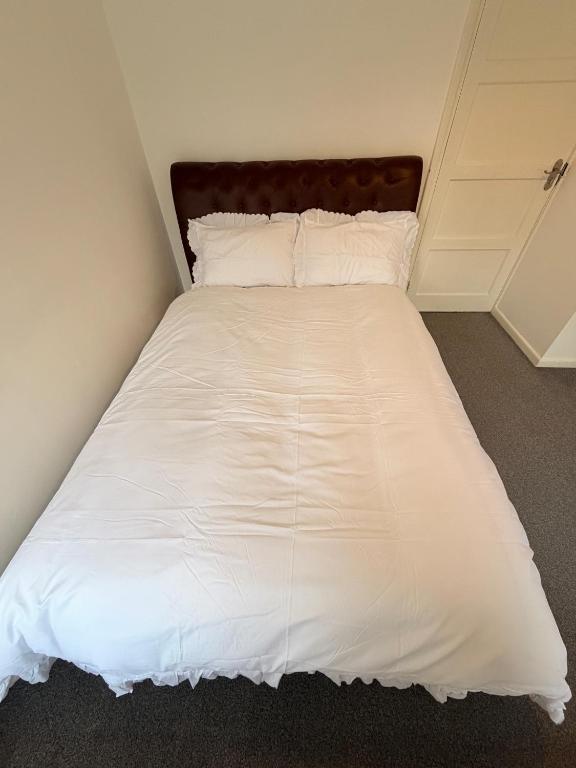 a bed with white sheets and pillows in a room at Precious House 2 in Leicester