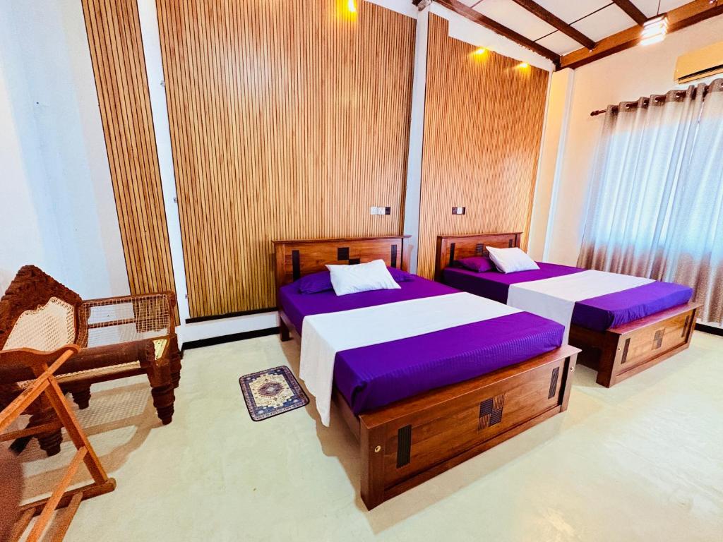 a room with two beds and a chair in it at Shehan Villa in Beruwala