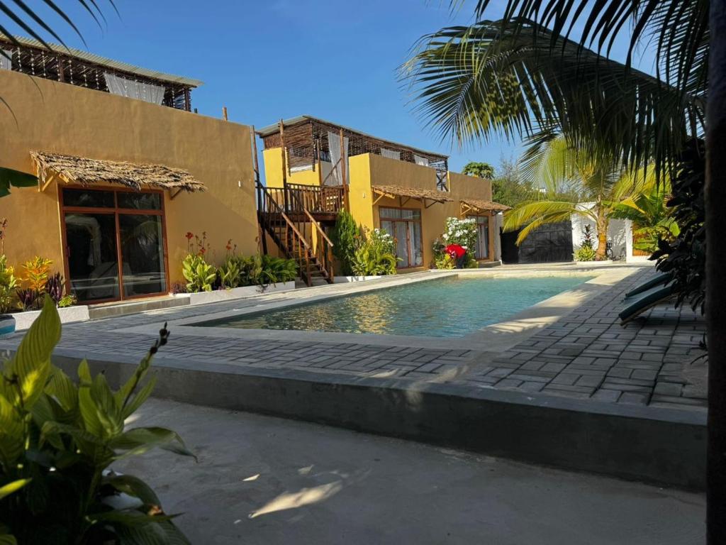 a swimming pool in front of a house at Happy Villas in Paje