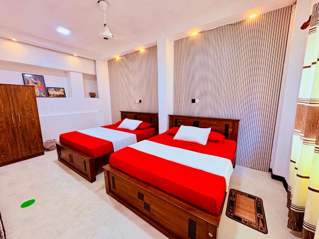 two beds in a bedroom with red and white sheets at Shehan Villa in Beruwala