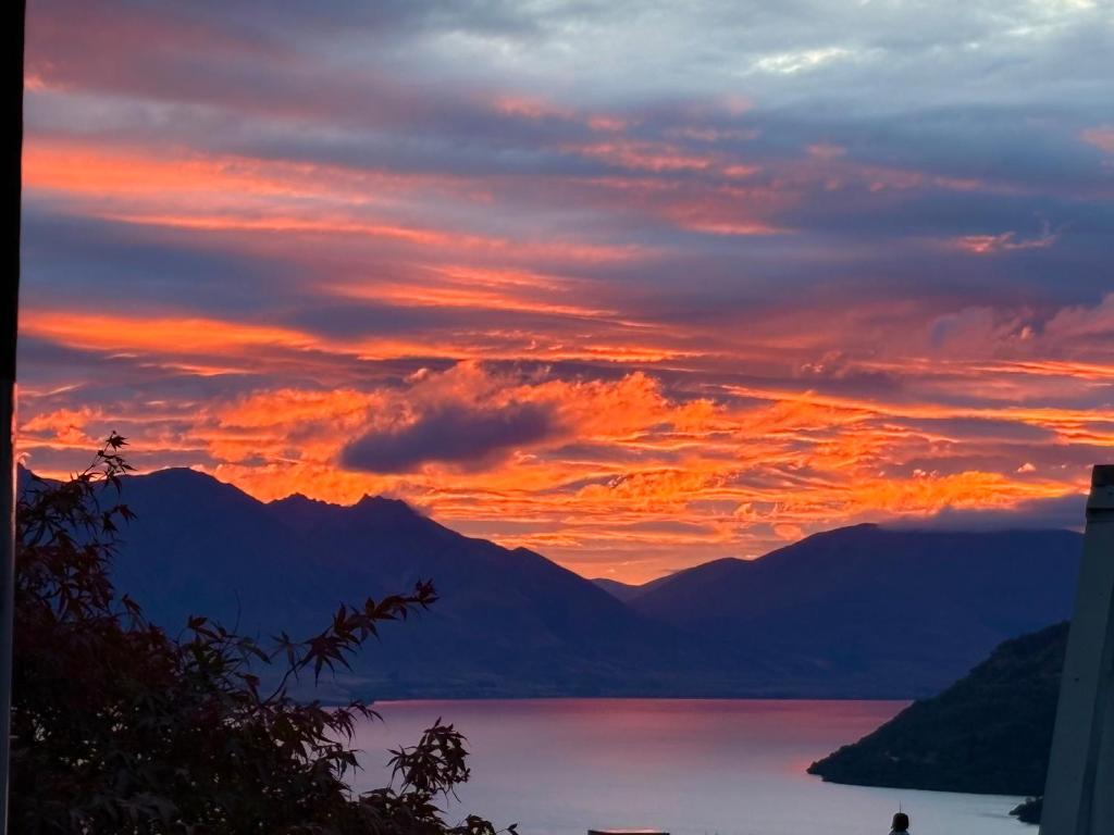 a sunset over a body of water with mountains at Sun Views Forest yet close to town in Queenstown