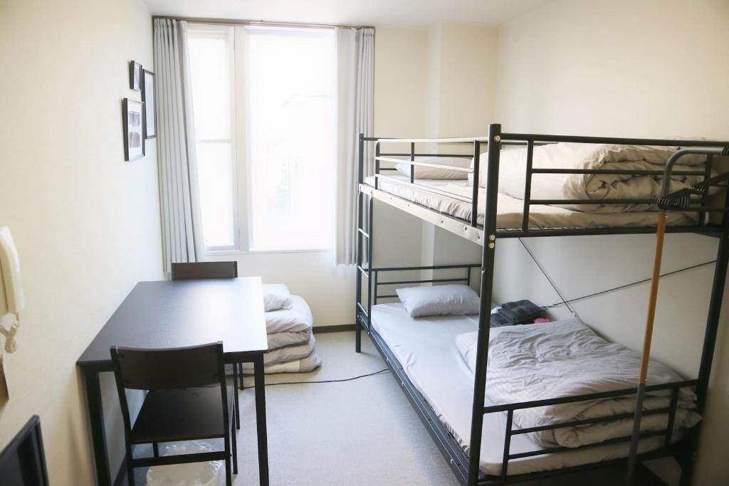 a room with three bunk beds and a table and a desk at Joinus Ise Apartment by Tranova in Ise