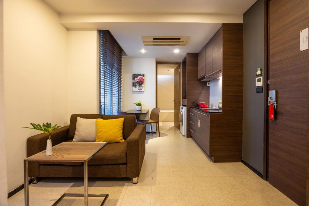 A compact residence lounge beside a kitchenette and entrance hall.