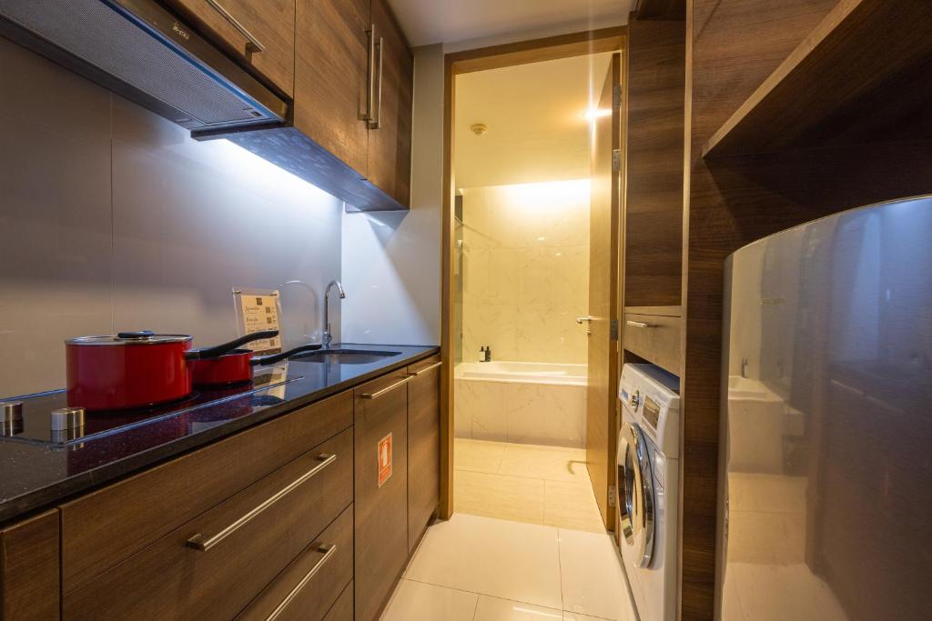 A compact apartment kitchen with cooking equipment, refrigerator and washing machine.