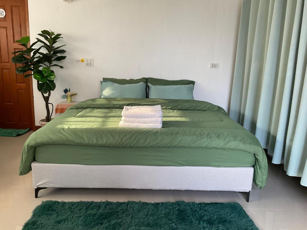 a bedroom with a large bed with green sheets at พี เจ เอ็ม โฮมสเตย์ in Ban Nong Chaeng