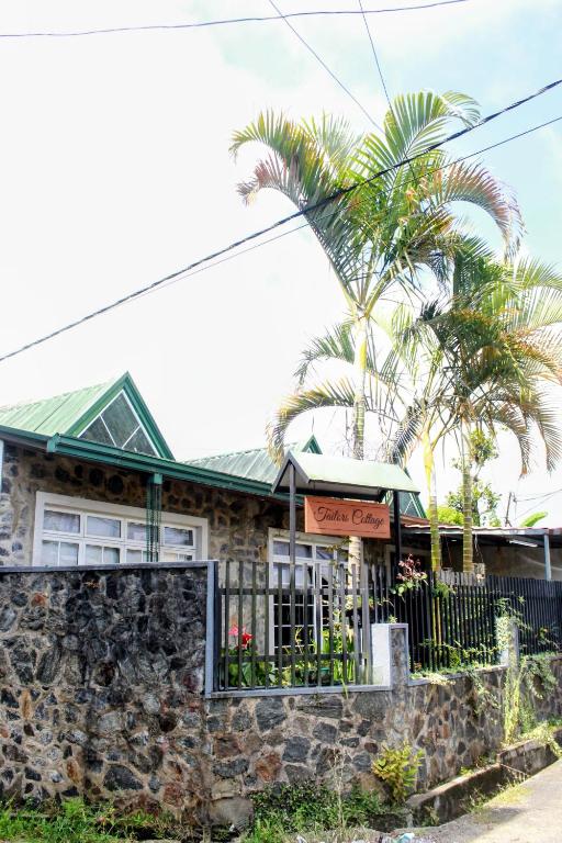 a house with a stone wall and a palm tree at Tailors Cottage in Hatton