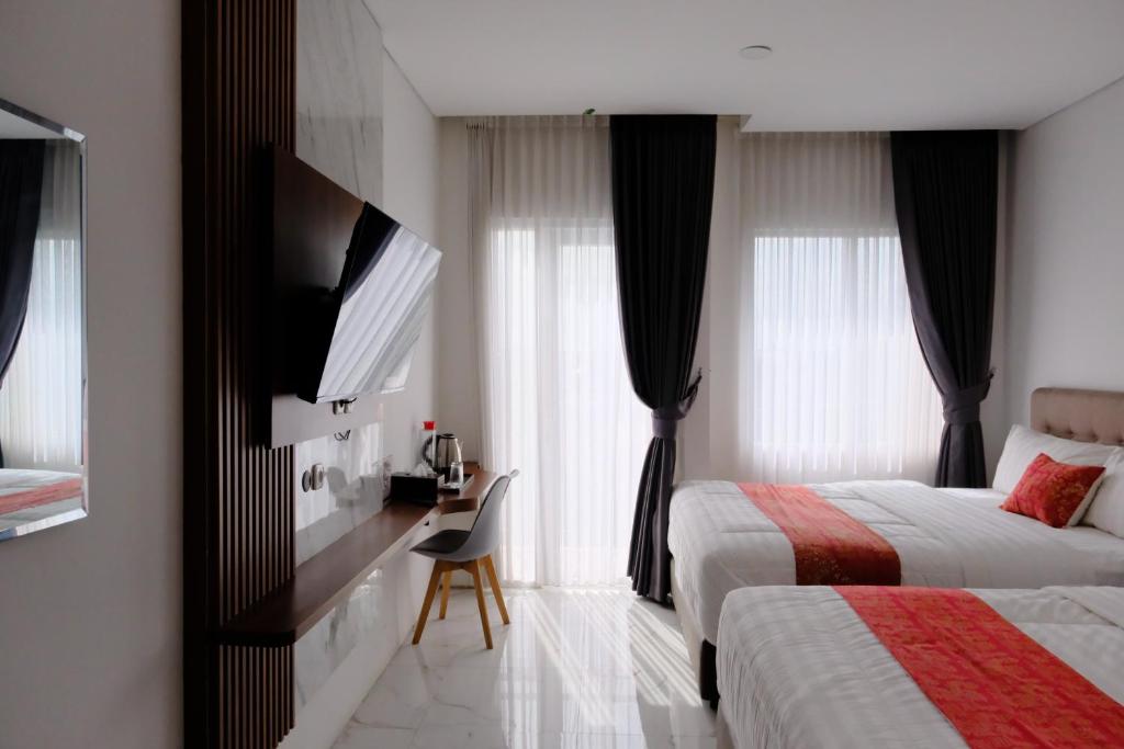 a hotel room with two beds and a desk at Grand Elhajj Banten in Tjipondoh Tiga