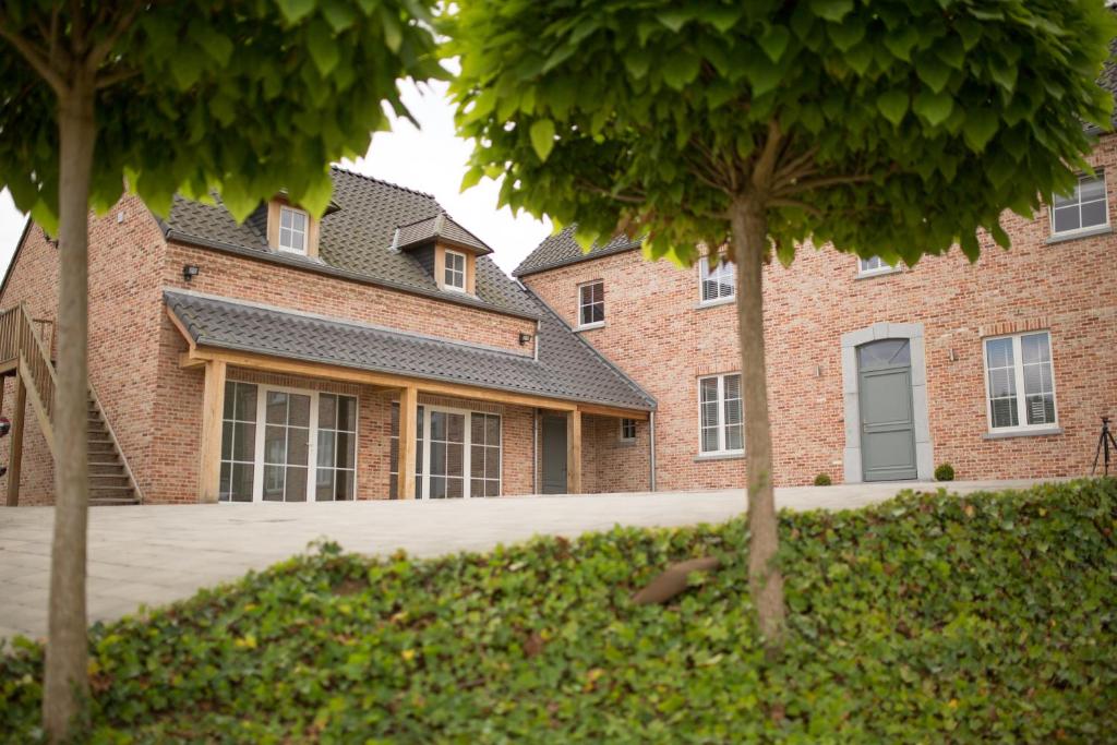a brick house with trees in front of it at l'Intervalle in Mont-Saint-Guibert