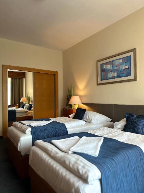 a hotel room with three beds and a mirror at Hotel Theresia in Kolín